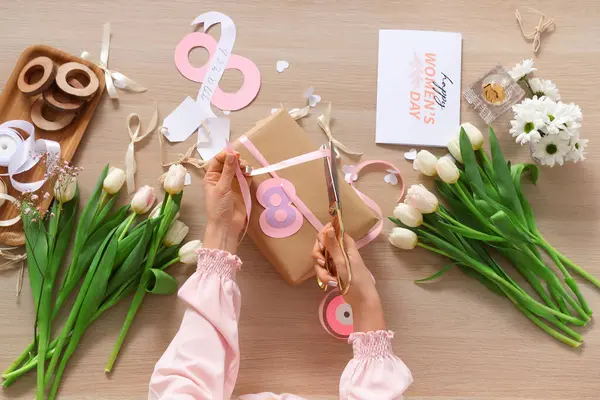 Kadın hediye paketi, tebrik kartı ve ahşap arka planda lale çiçekleri. Uluslararası Kadınlar Günü