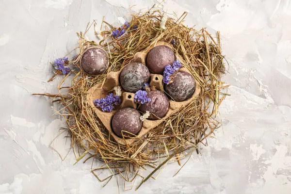 Çiçekli Paskalya yumurtaları ve gri arka planda saman.