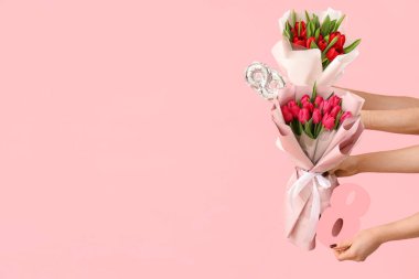 Lale buketleri, balon ve pembe arka planda kağıt figür 8 olan kadın elleri. Uluslararası Kadınlar Günü için Alışveriş