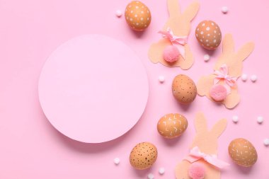 Paskalya yumurtaları, kağıt tavşanlar ve pembe arka planda pembe boş kart. Üst görünüm