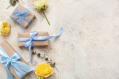 Paketlenmiş hediye kutularıyla zarif kompozisyon ve arka planda bahar çiçekleri süslemesi