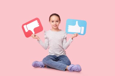 Pembe arka planda oturan ikonları seven ve sevmeyen küçük kız