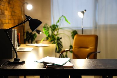 Geceleri karanlık ofisteki masada panosu olan lamba, yakın plan.