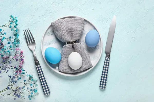 Paskalya için güzel bir masa, açık mavi arka planda yumurtalar ve çiçekler.