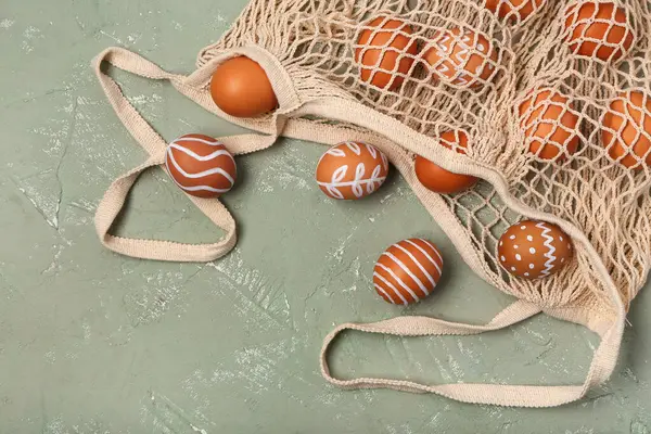 Gri arka planda boyanmış Paskalya yumurtaları olan ip torbası.