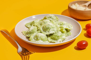 Sarı zemin üzerinde peynir olan lezzetli bir ravioli tabağı.