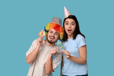 Mavi arka planda kağıt balıklarıyla kılık değiştirmiş genç şok olmuş arkadaşlar. 1 Nisan kutlamaları