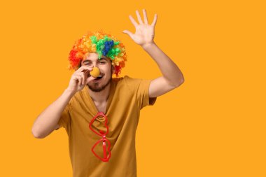 Sarı arka planda komik palyaço kılığına girmiş yakışıklı genç adam. 1 Nisan kutlamaları