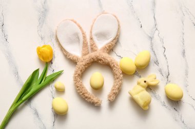 Paskalya yumurtaları ve beyaz mermer arka planda lale çiçeğiyle tavşan kulakları