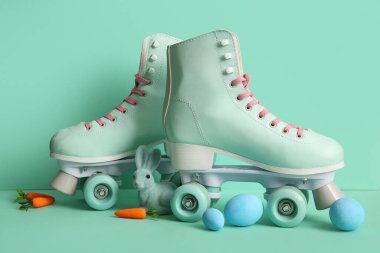 Paskalya yumurtaları, oyuncak tavşanlar ve turkuaz arka planda havuçlarla klasik patenler.