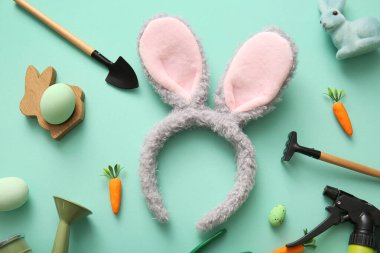 Paskalya yumurtası ve turkuaz arka planda bahçıvan aletleri olan tavşan kulaklı.