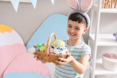 Evde paskalya sepetiyle tavşan kulağı takan şirin bir çocuk.