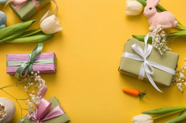 Paskalya tavşanı hediye kutuları ve turuncu arka planda çiçekler.