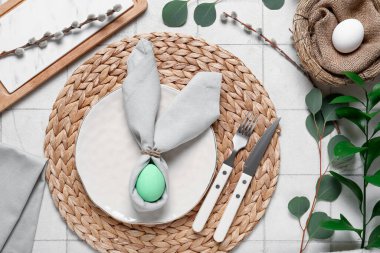 Paskalya için çok güzel bir masa. Beyaz fayanslı yumurta ve yeşil dalları var.