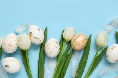 Mavi arka planda Paskalya yumurtaları ve tüyleri olan laleler