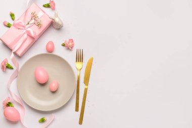Beyaz arka planda pembe hediyeler, çiçekler ve yumurtalar olan şirin Paskalya sofrası.