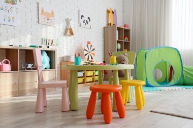 Anaokulunda masa ve oyuncaklarla dolu bir oyun odası.