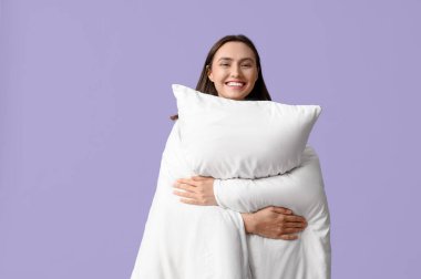 Leylak arka planında battaniyesi ve yastığı olan güzel genç bir kadın.