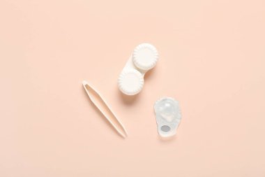 Bej arka planda kontakt lens ve cımbız içeren konteynır