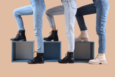 Bej arka planda farklı botlar giyen kadın bacaklar.