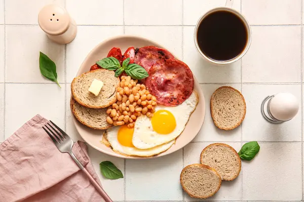 Lezzetli İngiliz kahvaltısı ve beyaz fayanslı bir fincan kahve.