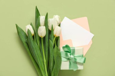 İçinde boş kart, hediye kutusu ve yeşil arka planda beyaz laleler olan zarf.
