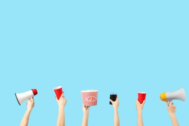 Ellerinde patlamış mısır, içki ve megafonla mavi arka planda