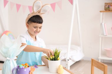 Tavşan kulağı takan şirin bir çocuk Paskalya süslemeleri yapıyor.