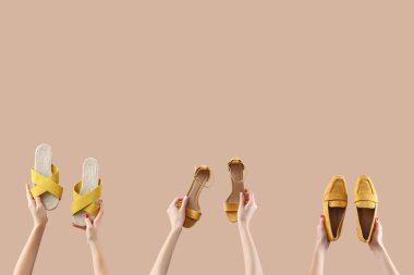 Bej arka planda farklı sandaletler tutan kadın eller.