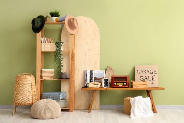 İstenmeyen pek çok şey ve kartondan yapılmış GARAGE satışı yeşil duvarın yanında.