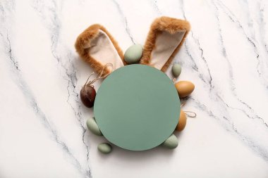 Paskalya yumurtalı tavşan kulakları ve beyaz mermer arka planda boş tebrik kartı.