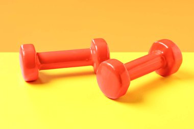 Renkli arka planda bir çift turuncu dambıl.