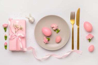 Beyaz arka planda pembe hediyeler, çiçekler ve yumurtalar olan şirin Paskalya sofrası.