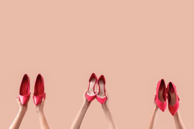 Bej arka planda farklı ayakkabılar tutan kadın eller.