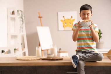 Evdeki masada oturan, bir kase mısır gevreği yüzüğüyle sevimli küçük bir çocuk.