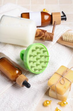 Silikon kafa masajı fırçası, bej kaplama arka planda kozmetik ürünler, sabun ve havlu.