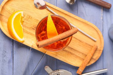 Lezzetli bir bardak eski moda kokteyl ve mavi ahşap arka planda portakal dilimleri.