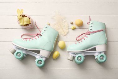 Beyaz ahşap arka planda Paskalya yumurtası ve oyuncak tavşanlı klasik patenler.