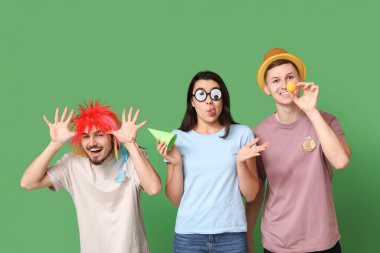 Yeşil arka planda kağıt balıklarıyla kılık değiştirmiş komik arkadaşlar. 1 Nisan kutlamaları