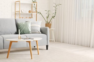 Gri kanepesi, masası ve raf ünitesi olan modern oturma odası.