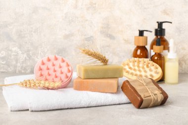 Saç derisi masaj aletleri, şampuan çubukları ve grunge grisi arka planda kozmetik ürünler.