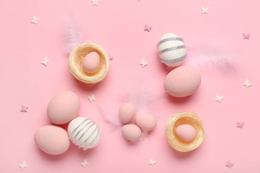 Pembe arka planda boyanmış Paskalya yumurtaları ve yuvaları ile kompozisyon