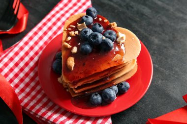 Kalp şeklinde leziz gözleme tabağı, koyu arkaplanda yabanmersini ve reçel, yakın plan. Sevgililer Günü kutlaması