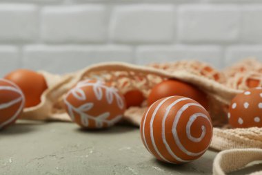 Gri masanın üzerinde boyanmış Paskalya yumurtaları olan bir ip torbası.