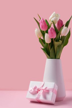 Güzel laleli vazo ve pembe arka planda hediye kutusu. Uluslararası Kadınlar Günü