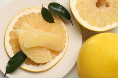 Lezzetli bir bütün ve beyaz arka planda parçalarla kesilmiş pomelo meyveleri.