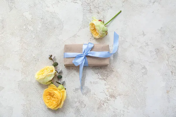 Zarif paketlenmiş hediye kutusu ve arka planda bahar çiçekleri dekoru