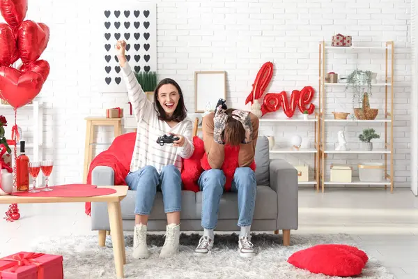 Evde video oyunu oynayan genç bir çift. Sevgililer Günü kutlaması