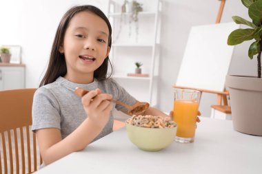 Evdeki masada bir kase mısır gevreği yüzüğüyle sevimli bir Asyalı kız.