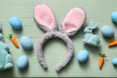 Tavşan kulaklı, paskalya yumurtası ve yeşil ahşap arka planda havuç